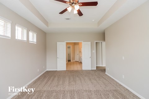 a spacious living room with carpet and a ceiling fan