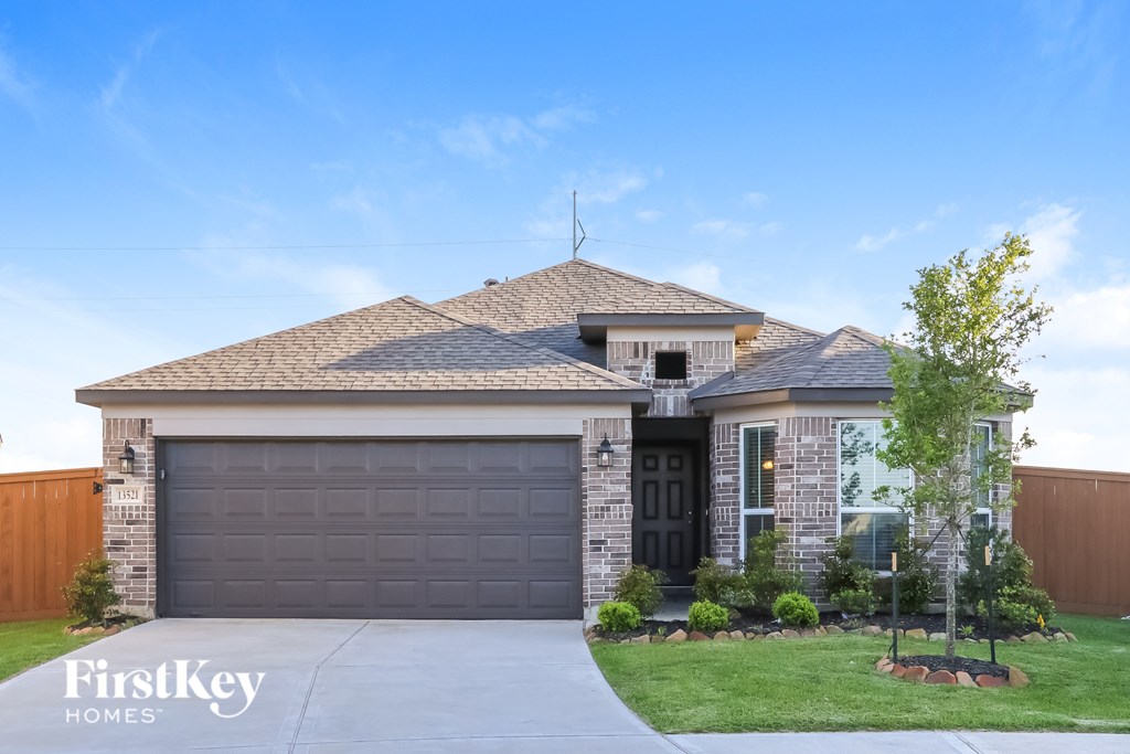 A house with a garage door and a tree in front.