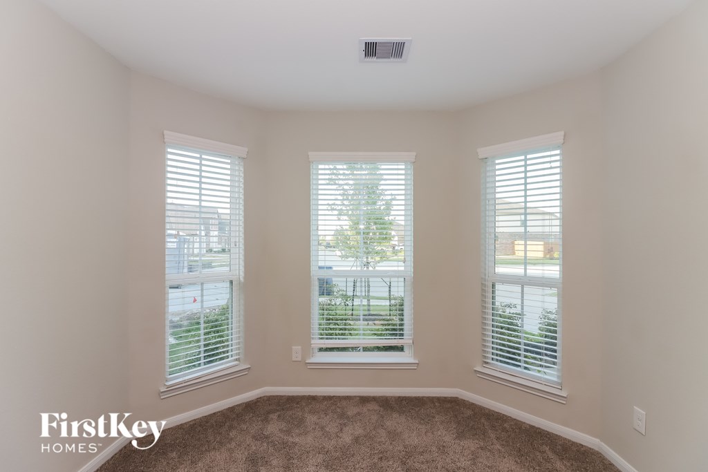 A room with three windows and a carpeted floor.