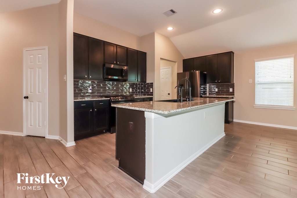 A kitchen with a white island and dark brown cabinets.