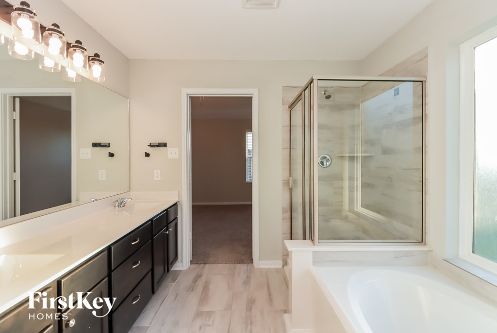 A bathroom with a tub, sink, and mirror.