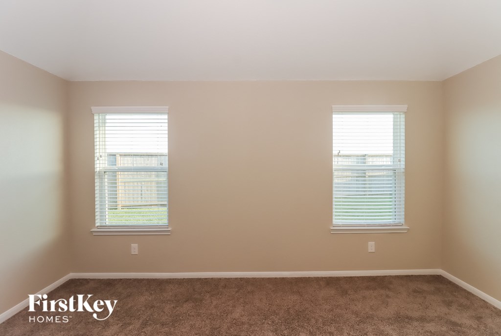 A room with two windows and a carpeted floor.
