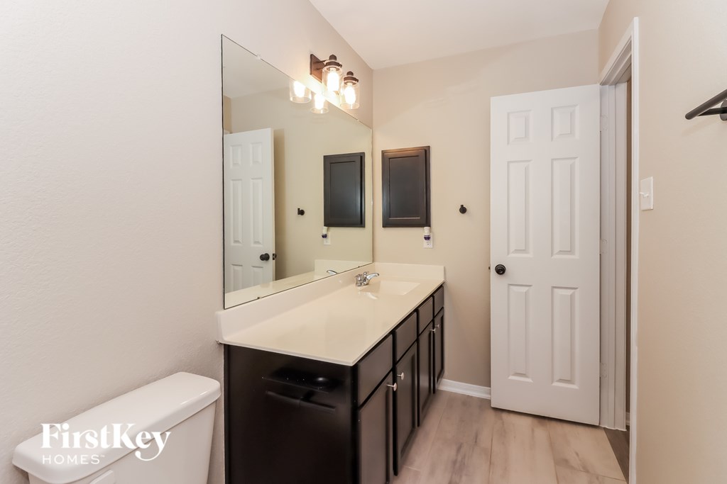 A bathroom with a white counter top and a white toilet.