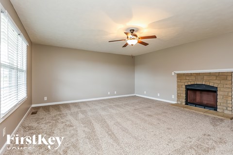 A spacious room with a fireplace and a ceiling fan.