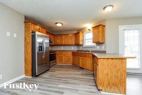 A kitchen with wooden cabinets and a stainless steel refrigerator.
