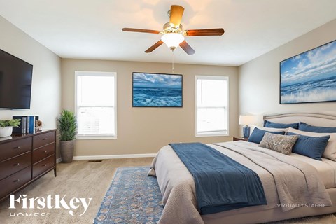 A bedroom with a large bed and a ceiling fan.