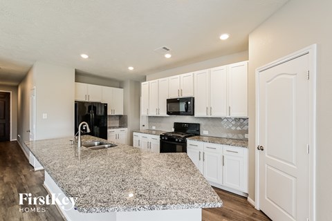 A kitchen with granite countertops and white cabinets.