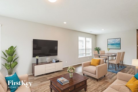A living room with a flat screen TV, a coffee table, and a dining table with chairs.