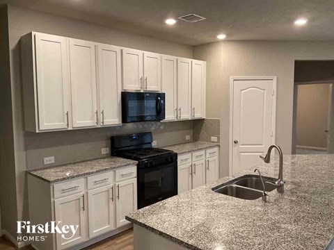 A kitchen with granite countertops and white cabinets.