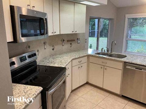 A kitchen with white cabinets and granite countertops.