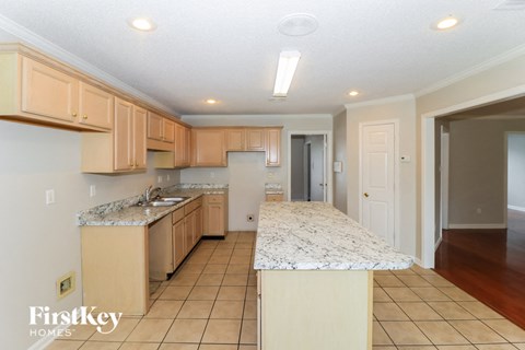 A kitchen with a marble counter top and wooden cabinets.