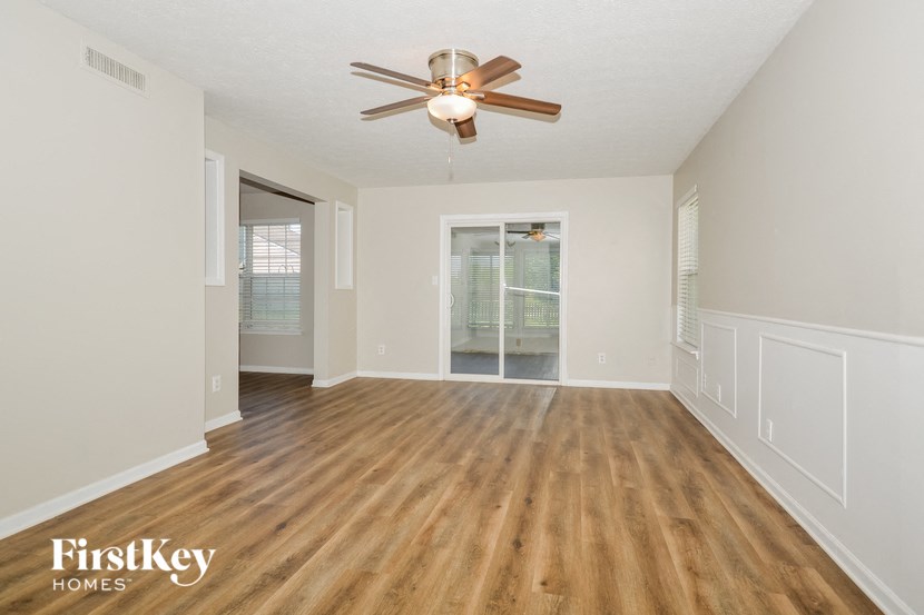 an empty living room with hardwood floors and a ceiling fan