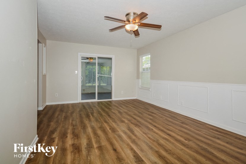 an empty living room with wood floors and a ceiling fan