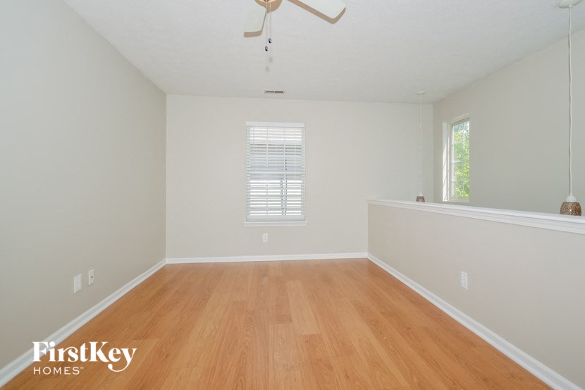 a bedroom with a hardwood floor and white walls and a window