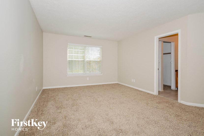 a spacious bedroom with carpet and a door to the bathroom