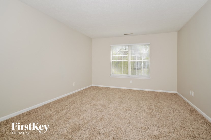 a spacious room with carpet and a window