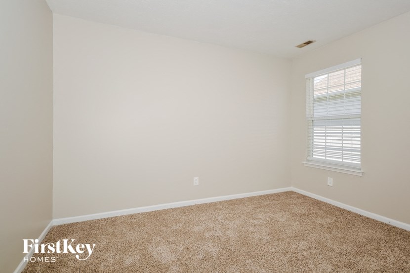 a bedroom with a carpeted floor and a window