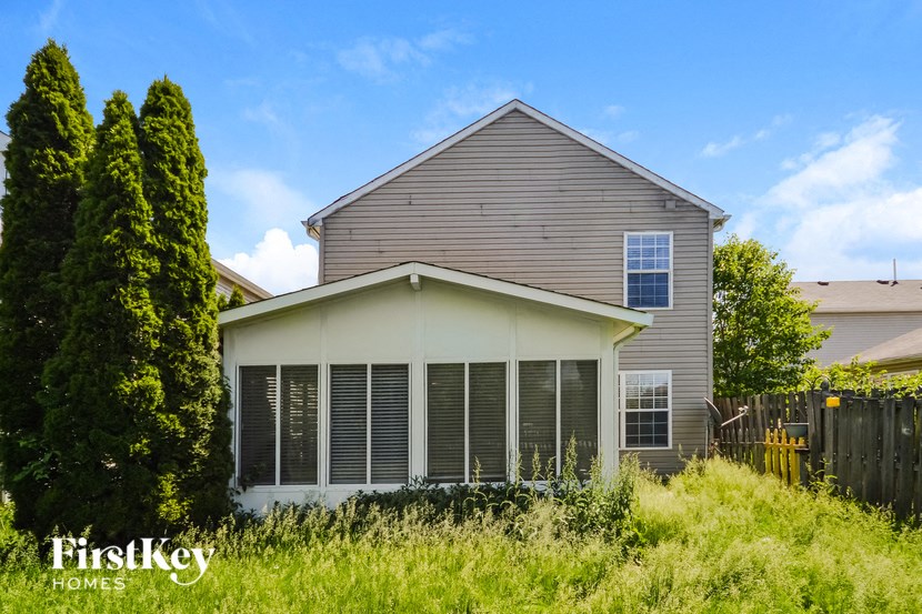 the front of a house with large windows and a yard with tall grass