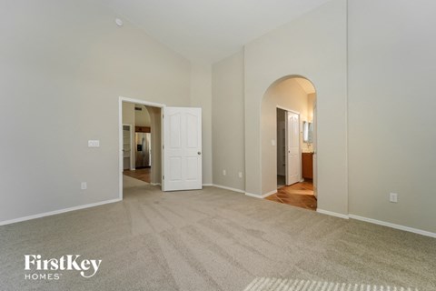 a spacious living room with a carpeted floor and a door to a bedroom
