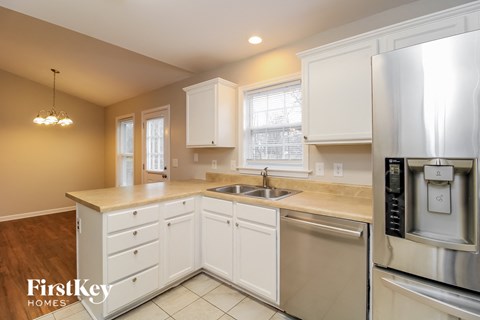 A kitchen with a stainless steel refrigerator and white cabinets.