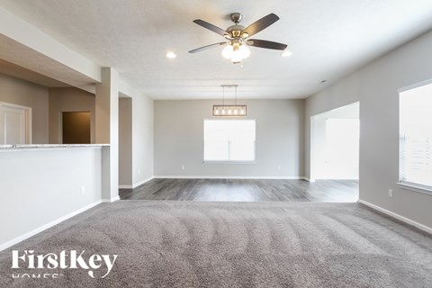 A spacious room with a ceiling fan and a rug on the floor.