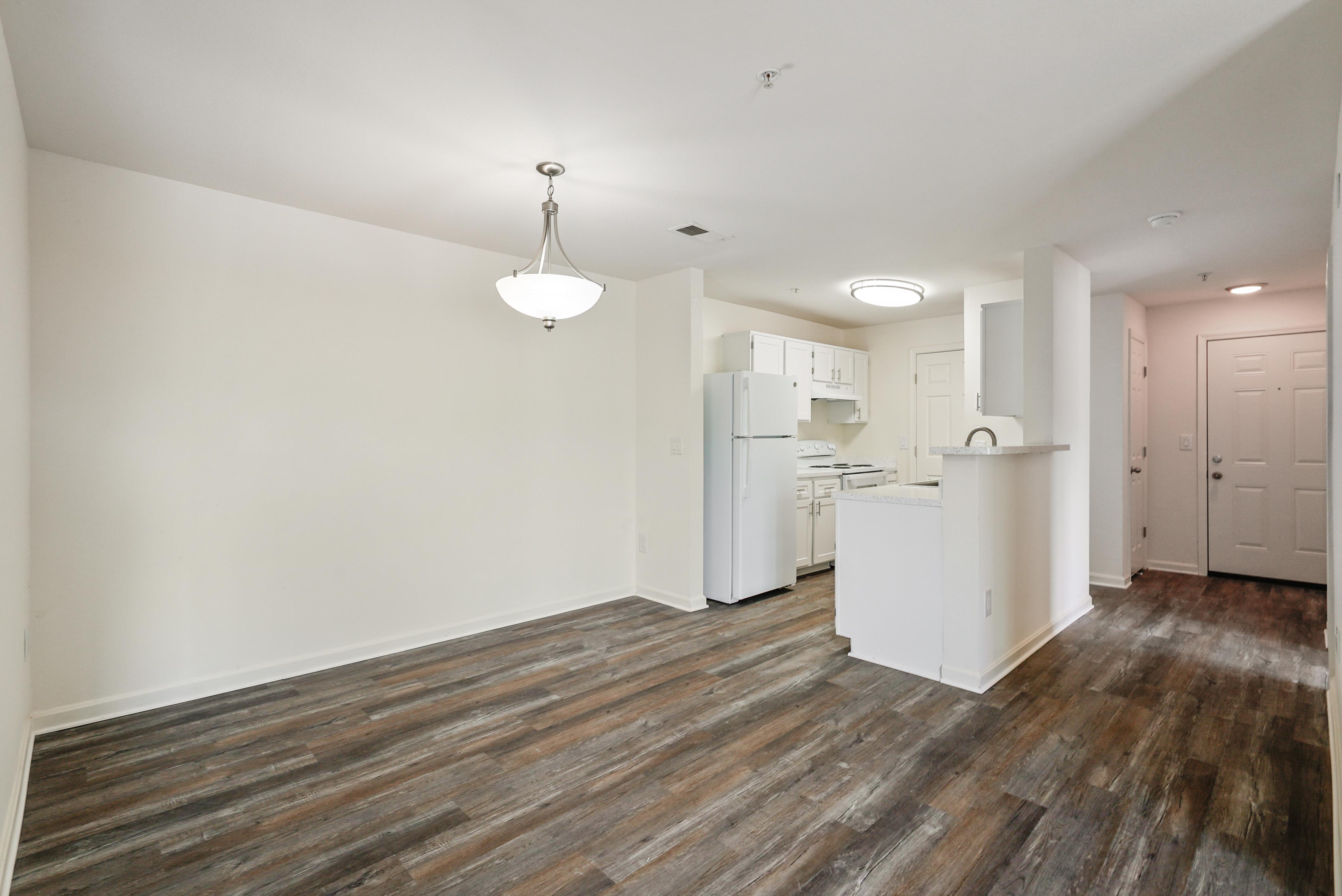 A kitchen area with a white refrigerator and wooden flooring.