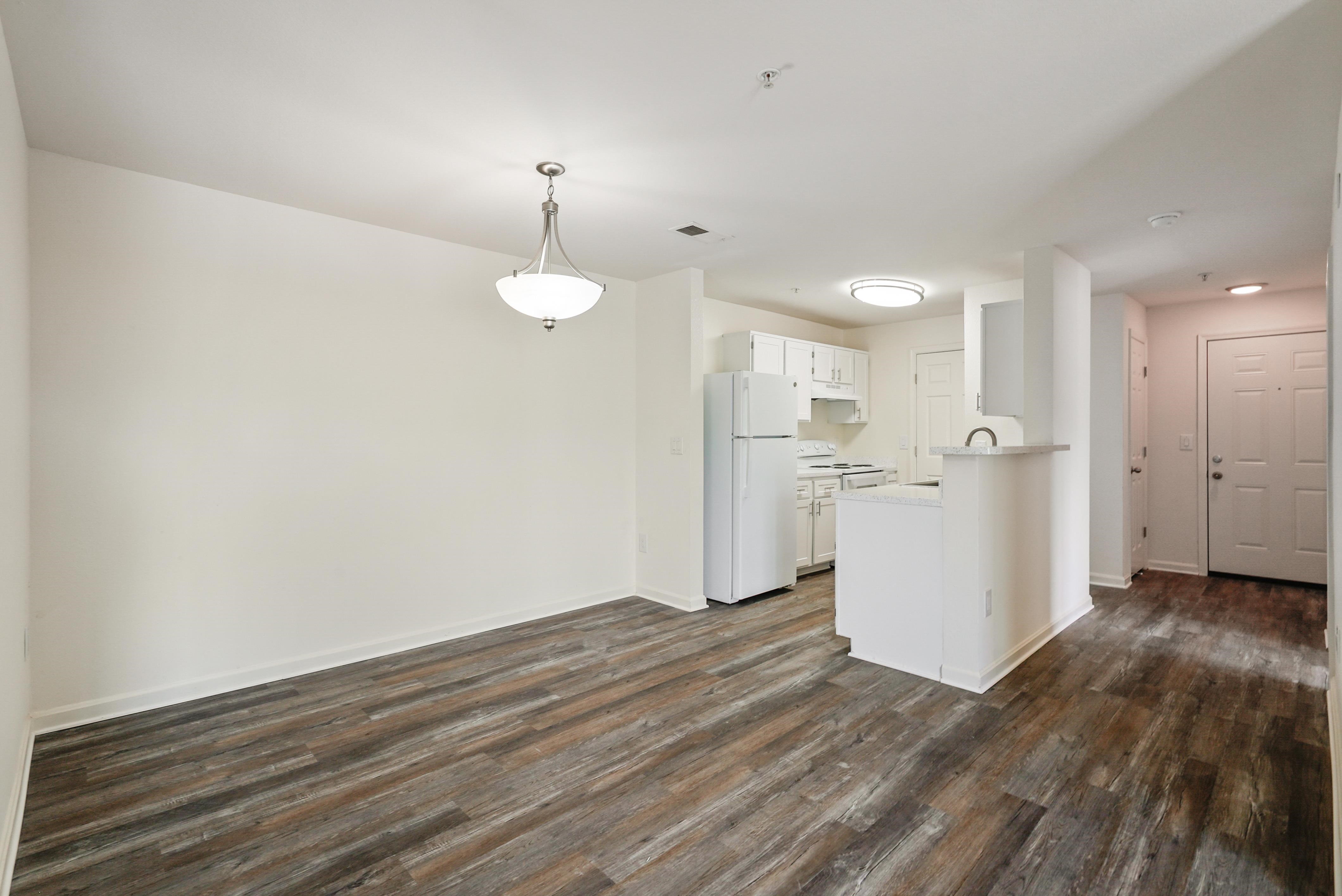 A kitchen area with a white refrigerator and wooden flooring.
