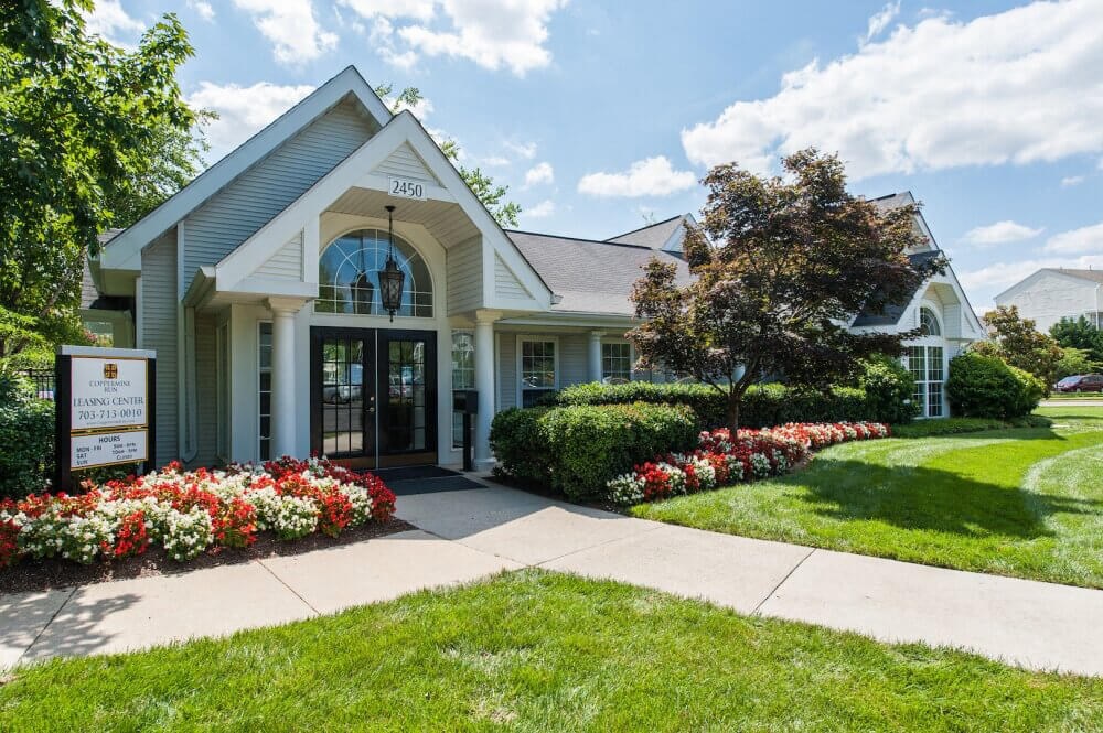 the front entrance of a white house with a sidewalk and flowers