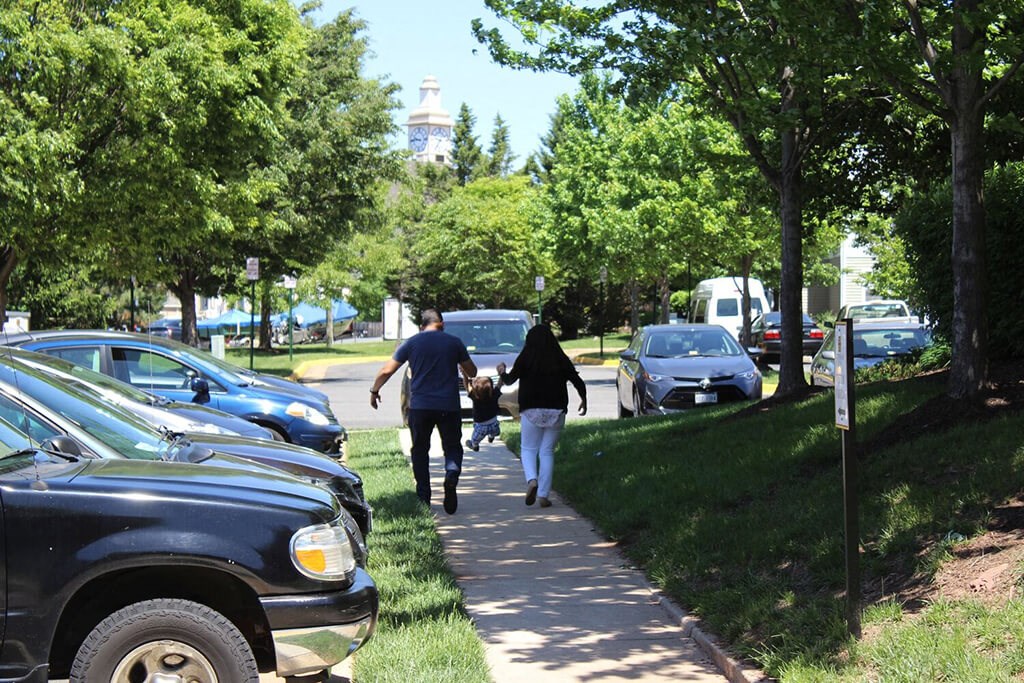 a family walking down a sidewalk in a parking lot