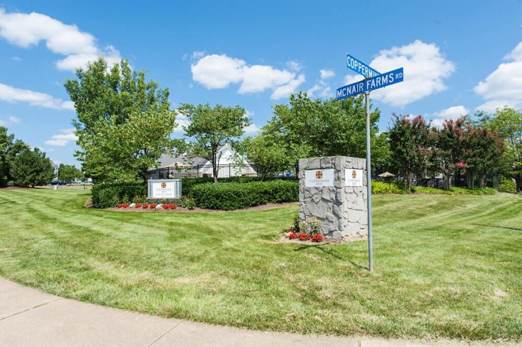 a street sign in the grass next to a sidewalk