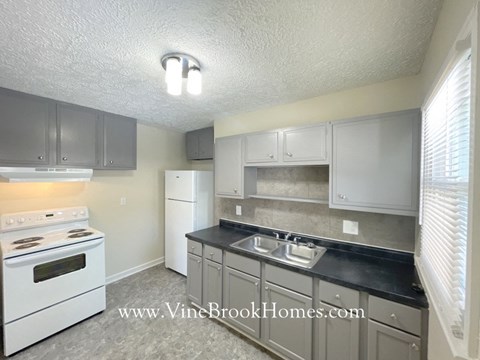 A kitchen with a white stove top oven and a white refrigerator.