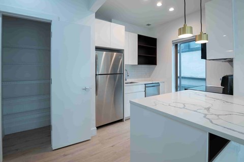 A modern kitchen with a marble countertop and stainless steel appliances.