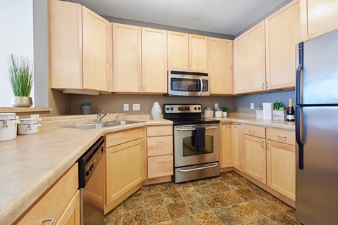 A kitchen with wooden cabinets and a tile floor.