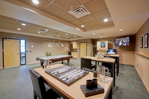 A conference room with a tables and chairs and a TV on the wall.