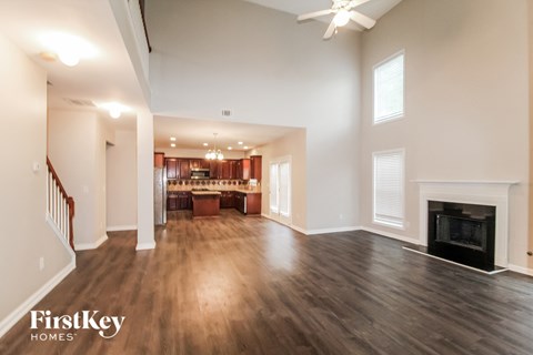 an empty living room with a fireplace and a kitchen