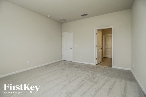 a master bedroom with carpet and a door to the bathroom