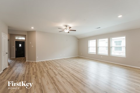 A spacious room with wooden flooring and a ceiling fan.