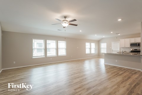 A spacious room with wooden floors and a ceiling fan.