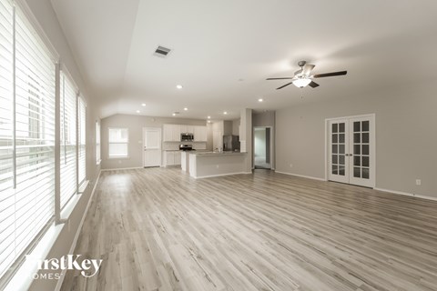 A spacious room with a ceiling fan and wooden flooring.