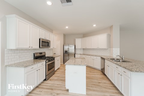 A kitchen with white cabinets and a white island.