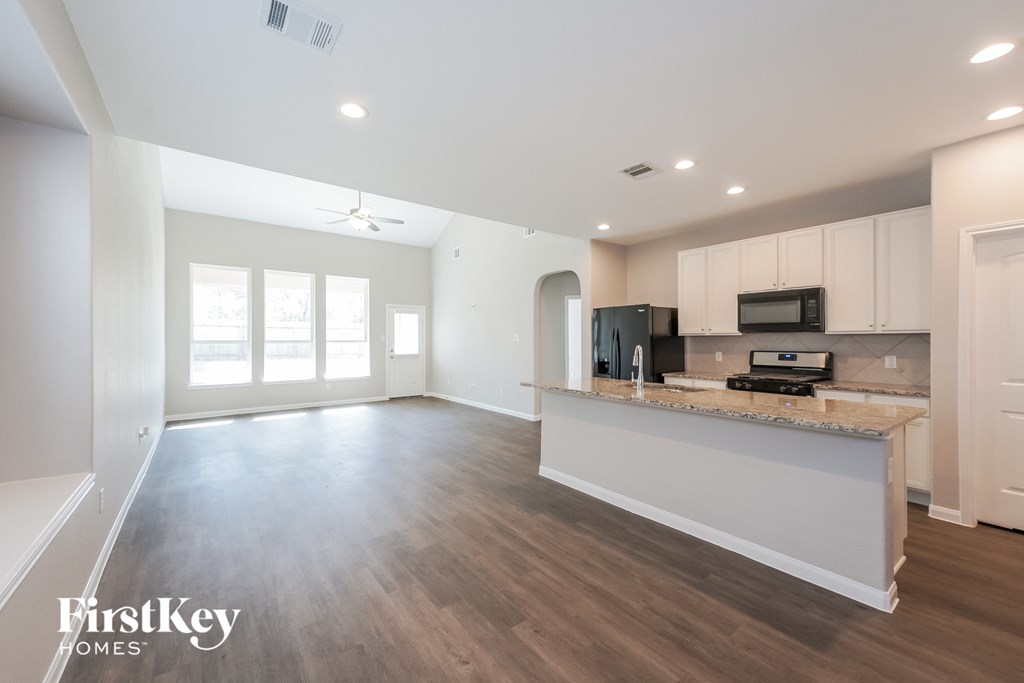 a kitchen and living room with white cabinets and a counter top