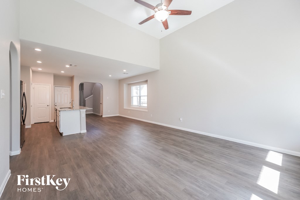 a living room with white walls and a ceiling fan