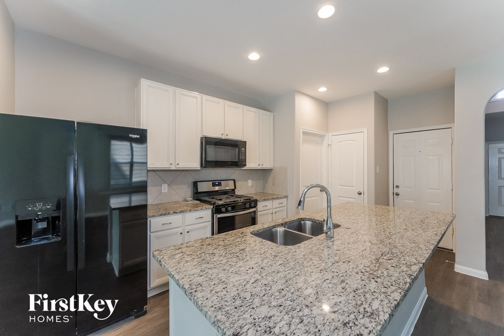 a kitchen with a granite counter top and a stainless steel refrigerator
