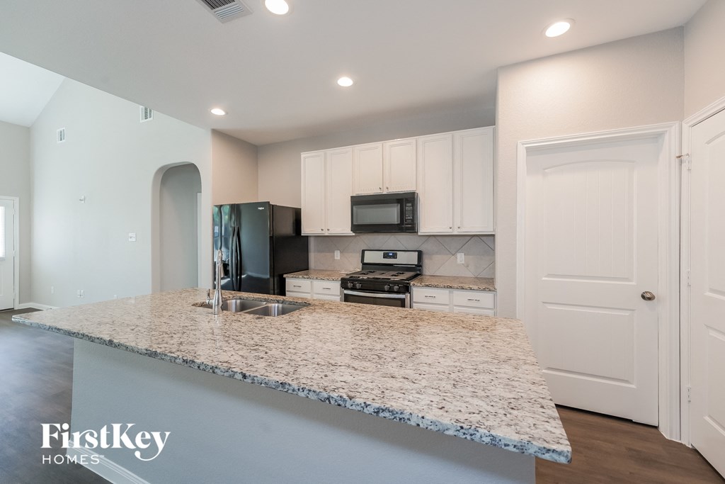 a kitchen with white cabinets and a granite counter top