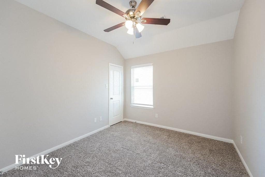 a bedroom with a ceiling fan and a carpet