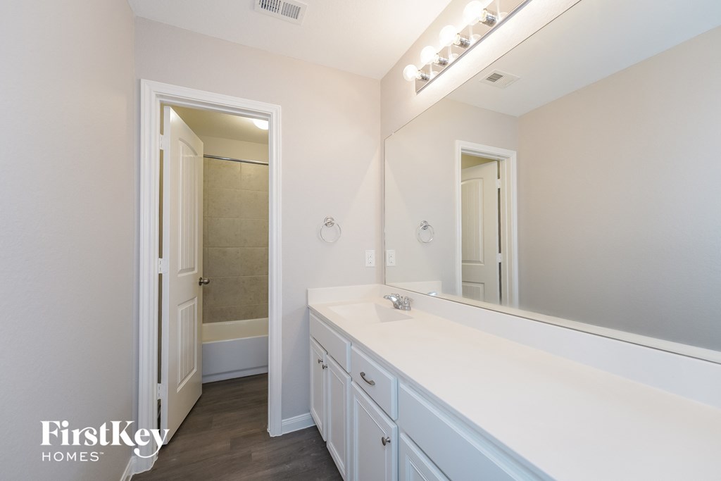 a white bathroom with a large mirror and a white counter top