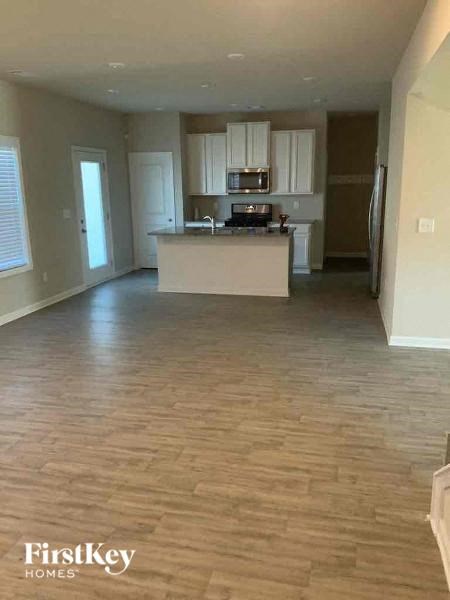 an empty living room and kitchen with wood flooring