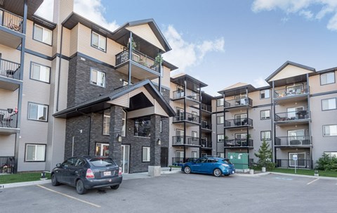 an apartment building with two cars parked in front of it