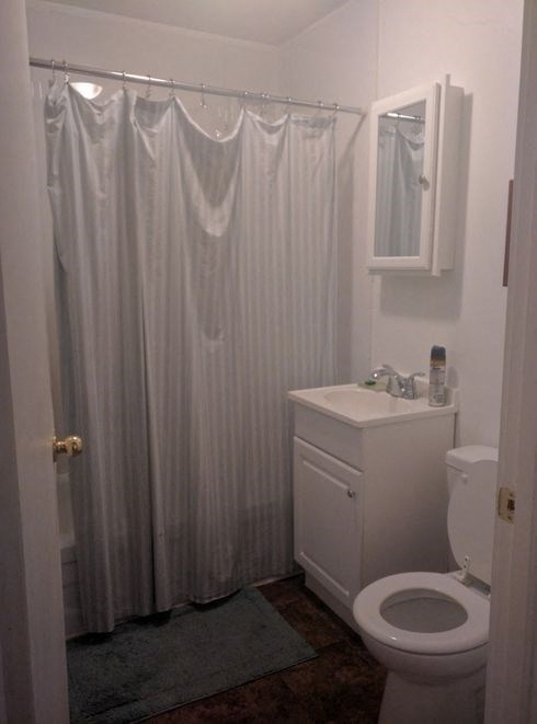 a white bathroom with a white shower curtain and a toilet