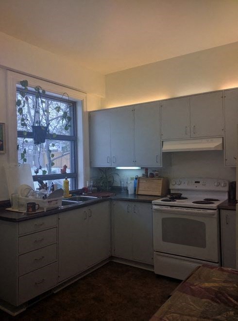 a kitchen with white cabinets and a stove and a window